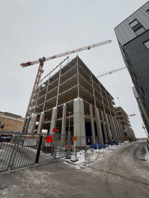 Nyproduktion med betongstomme och byggkranar mitt i staden